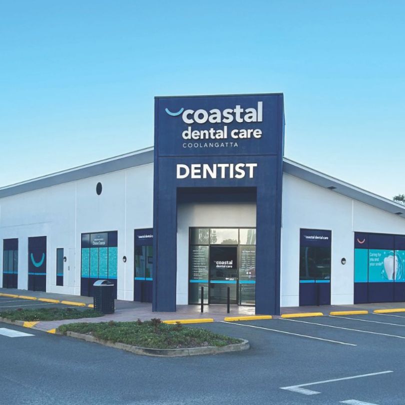 Store front of Coastal Dental Care, Dentist. A white building with dark blue features.