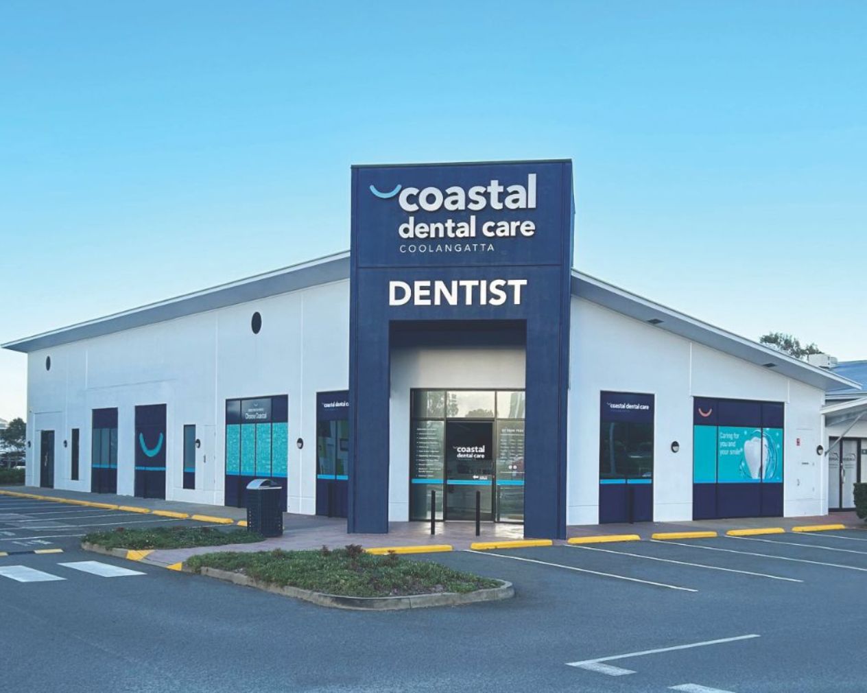 Store front of Coastal Dental Care, Dentist. A white building with dark blue features. 
